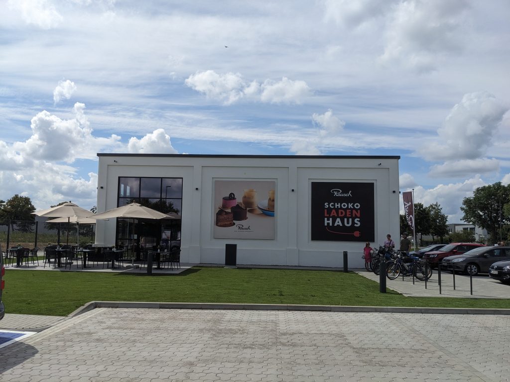 Schokoladenhaus mit Café und Werksverkauf und riesigen Ladepark